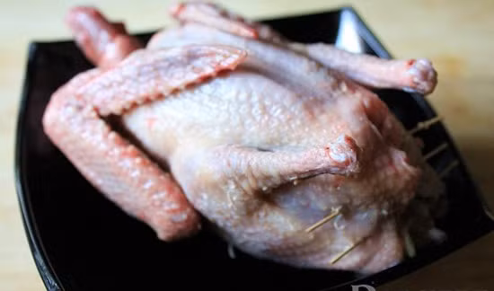 Hạt sen nấu khoảng 10 phút cho mềm. Trộn đều cốm, 1/2 chỗ hạt sen, thịt bằm, nấm, hành tím với hạt nêm và tiêu 5 phút. Dồn hỗn hợp thịt vào trong bụng bồ câu. Dùng vài chiếc tăm cài phần dưới bụng bồ câu cho kín. Ảnh: toinayangi.vn.