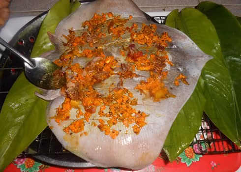 3. Cá đuối nướng nghệ. Nguyên liệu: Cá đuối, lá gừng, tinh bột nghệ, tỏi, hành tím, chanh, ớt tươi, nước mắm, muối, tiêu. Để nguyên cả con cá và dùng dao nhọn cắt dọc trên thân cá theo từng đường nhỏ để khi ướp cá dễ thấm gia vị hơn. Ảnh: monvietngon.vn.