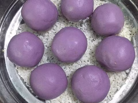 Làm ấm nước lá cẩm, cho vào nhồi cùng bột nếp cho dẻo mịn. Để bột nghỉ 15 phút đậy kín. Sau đó chia 10 viên bột đều nhau, vo viên bọc nhân vào giữa. Nếp ngâm xong đổ ra rổ cho thật ráo nước, trộn với muối. Ảnh: cookpad.com.