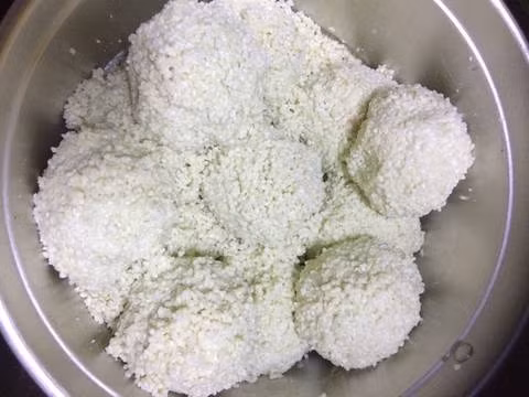 Dọn sẵn nồi hấp xôi, đổ nước hơn nửa nồi vào nồi dưới rồi bật bếp. Lấy một miếng màng nhựa bọc thực phẩm để lên chỗ trống, để một viên bột nếp vào, đậy lại bằng một màng bọc thực phẩm khác, rồi dùng chai tròn cán mỏng viên bột. Ảnh: cookpad.com.