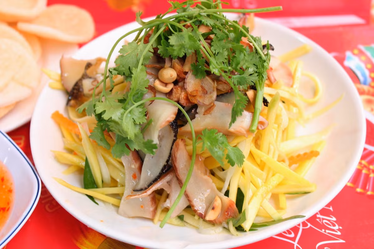 Su hào gọt vỏ thái sợi bóp chút muối xả lại nhiều lần cho bớt mặn bóp nước ráo. Pha nước mắm. Tỷ lệ 1:1:1 cho đường mắm chanh. Ớt tỏi tuỳ ý. Trộn tất cả lại với nhau. Thái rối rau thơm trộn vô. Bày trí ra đĩa ăn kèm bánh phồng tôm. Ảnh: hongngocfoody.blogspot.com.