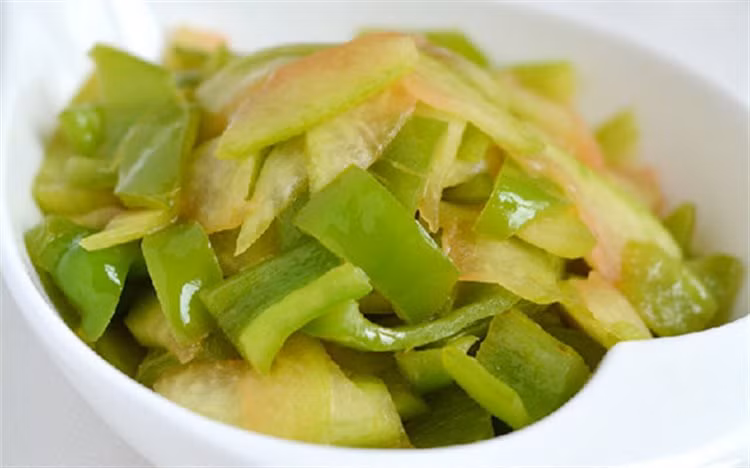 Ớt chuông xanh rửa sạch, thái miếng nhỏ vừa ăn. Làm nóng chảo dầu trên bếp, cho ớt chuông xanh vào xào. Tiếp đến cho cùi dưa vào xào, nêm muối vừa ăn xào chín tắt bếp rắc thêm tiêu cho thơm. Ảnh: Cooky.vn.