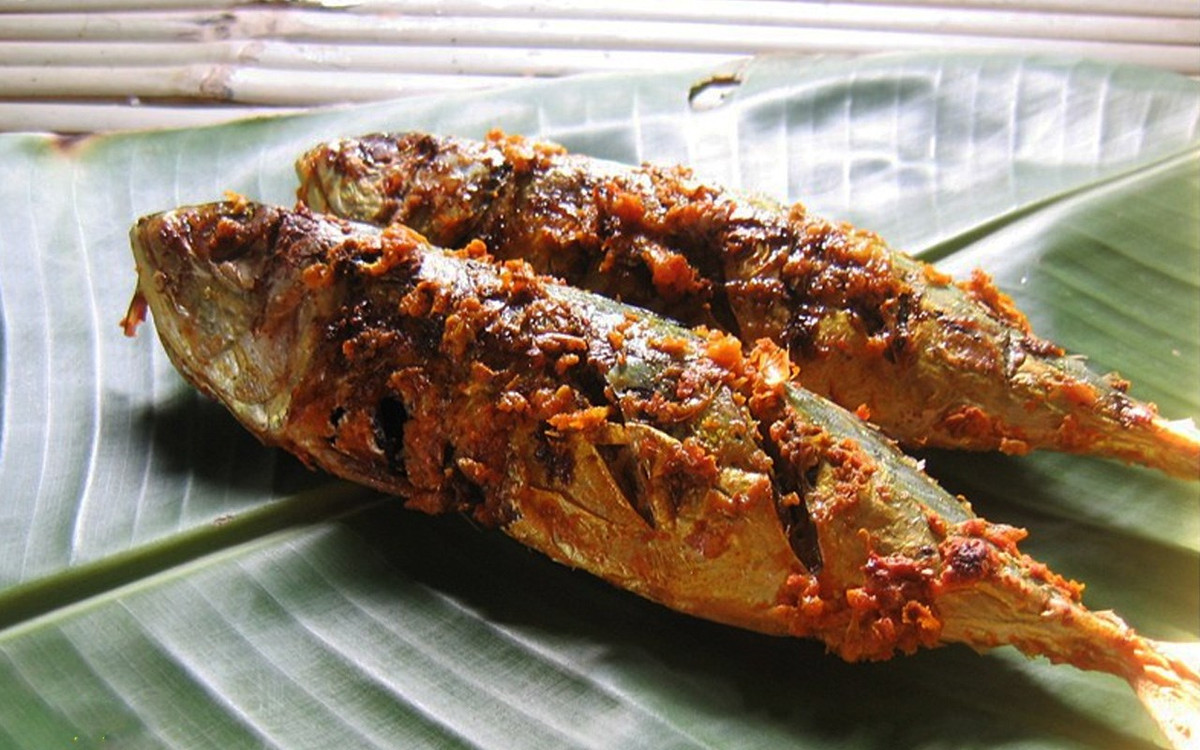 Có thể nướng cá thu gói lá chuối bằng than hoa hoặc thực hiện theo mẹo sau: Chọn một chiếc chảo dày rồi đặt cá vào chảo, sau đó đặt chiếc thớt lên. Khi lá chuối chuyển màu nâu đen là cá chín, mỗi mặt cá nướng khoảng 10 phút là được. Ảnh: cooky.vn.