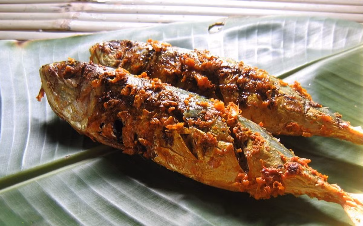 Có thể nướng cá thu gói lá chuối bằng than hoa hoặc thực hiện theo mẹo sau: Chọn một chiếc chảo dày rồi đặt cá vào chảo, sau đó đặt chiếc thớt lên. Khi lá chuối chuyển màu nâu đen là cá chín, mỗi mặt cá nướng khoảng 10 phút là được. Ảnh: cooky.vn.