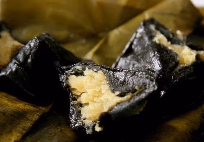 Lặn như làm bánh rán, làm mỏng bột ra và cho nhân vào giữa, sau đó gói kín nhân lại, ấn dẹp xuống, rắc ít vừng lên trên mặt bánh, cuối cùng bọc kín bằng lá chuối, bó chặt bằng lạt, đem hấp khoảng 30 phút sau khi nước sôi là được. Ảnh: Beemart.vn.