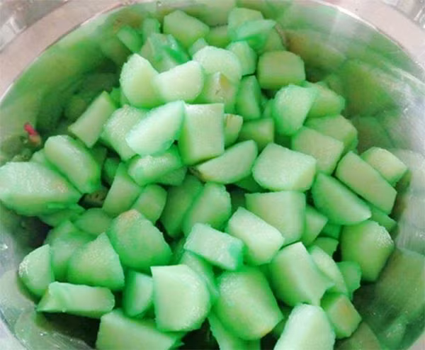 Cho củ năng đã nhuộm xanh xóc cùng với bột năng để bột phủ kín từng “hạt lựu”. Đun nồi nước sôi lớn, thả củ năng vào luộc đến khi chín nổi lên thì vớt ra, cho vào bát nước lạnh. Đậu xanh ngâm nước từ trước cho mềm, hấp chín, nghiền nhuyễn. Trộn 50g đường vào đậu xanh. Ảnh: Agiadinh.net.