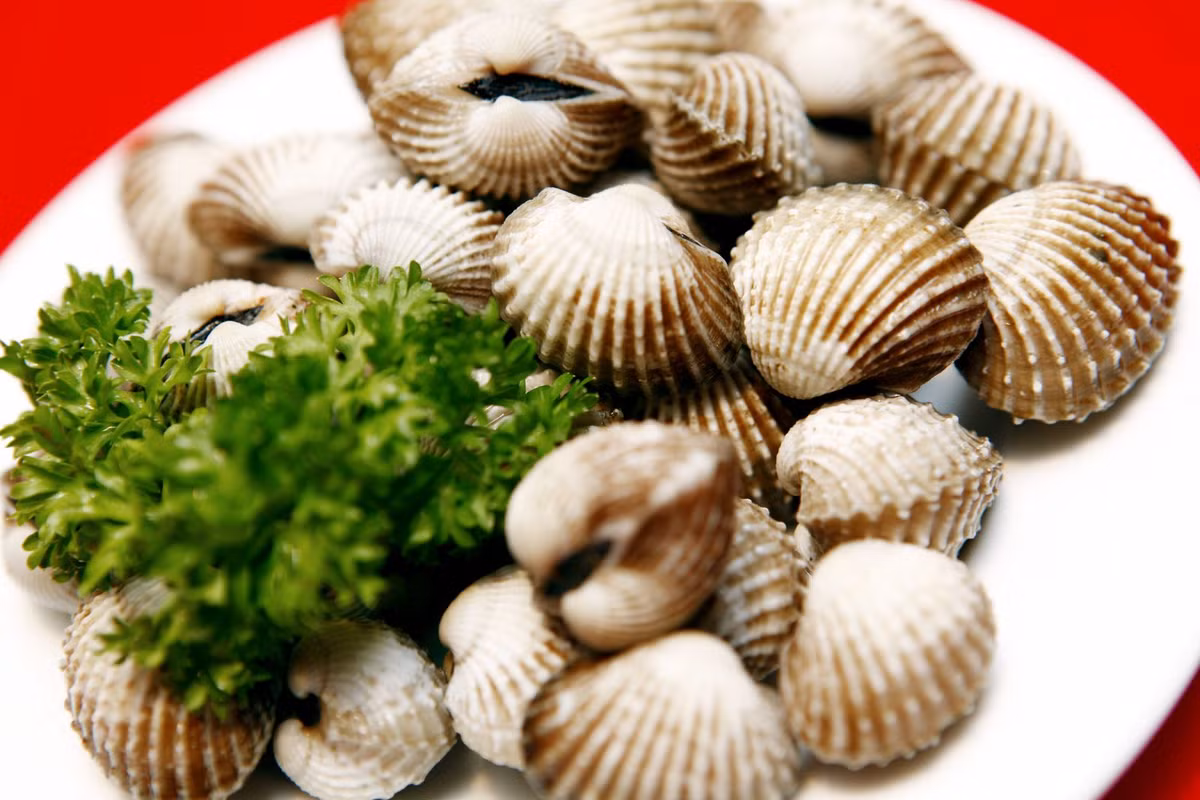 2. Sò huyết luộc sả. Nguyên liệu: Sò huyết, sả tươi, gừng. Rửa sạch sò huyết. Sả đập dập. Cho nước vào nồi, xếp sả vào, cho gừng tươi vào nấu sôi tầm 5 phút. Ảnh: jamja.vn.