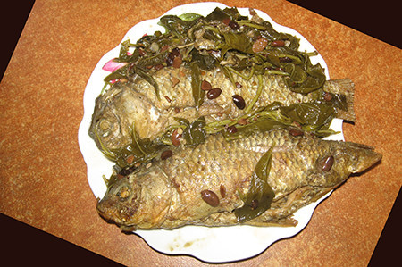 3. Cá diếc om lá cúc tần. Nguyên liệu: Cá diếc, lá cúc tần, gừng, riềng, lá cúc tần, gia vị. Khi kho cá, xếp một lượt lá cúc tần xuống dưới, đến một lượt cá, xen kẽ là gừng, riềng, trên cùng là một lượt lá cúc tần nữa, thêm gia vị, nước hàng, dầu ăn. Cá kho liu riu lửa tới khi sền sệt khi nhấc xuống, dùng nóng với cơm rất ngon. Ảnh: toquoc.vn.