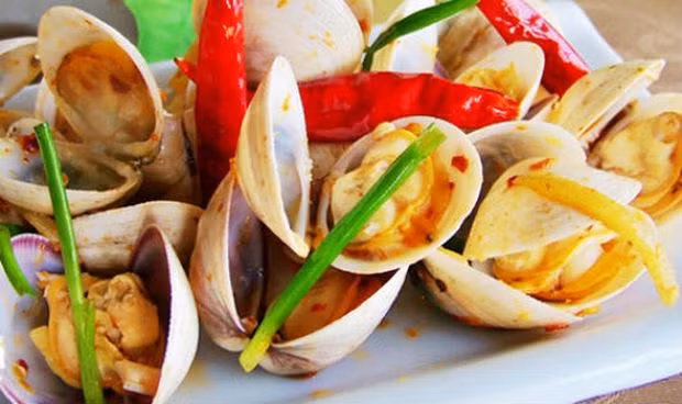 Làm nóng dầu ăn trong chảo, xào gừng, ớt, và tỏi, phần thân trắng của hành lá ở ngọn lửa trung bình. Sau đó vặn to lửa, cho ngao vào. Thêm muối và đảo ngao trong 1 phút để gia vị ngấm vào thịt ngao. Ảnh: baophapluat.vn.