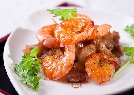 Đảo đều cho tôm chín thì nêm đường, nước mắm, nước màu kho cá, rang lửa to cho gia vị rút hết vào tôm và thịt, sau đó cho hành, tỏi, ớt băm vào đảo đều cho dậy mùi thơm, nếm lại cho vừa ăn. Cuối cùng bạn cho hành lá thái nhỏ vào là tắt bếp. Ảnh: tomhum.vn.