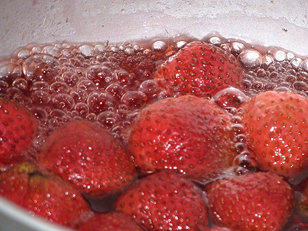 Bắc 1 cái chảo to lên bếp, cho đường cùng với dâu tây vào. Bạn đun nhỏ lửa, khi mứt sôi, đường sẽ tan chảy thành nước và có màu hồng nhạt đẹp mắt. Ảnh: Emvaobep.com.