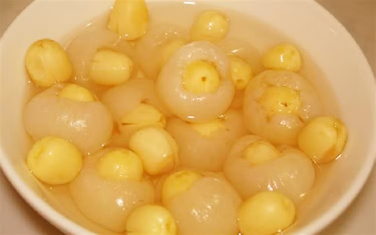 Lọc lại nước luộc hạt sen, cho đủ khoảng 1 lít là được. Cho thêm đường vào nồi hạt sen, đặt lên bếp đun sôi sao cho đường tan hoàn toàn. Tiếp đến bạn cho phần nhãn đã bọc hạt sen vào trong nồi và đun trong khoảng 10 phút cho thật ngấm đường rồi tắt bếp. Ảnh: Cooky.vn.