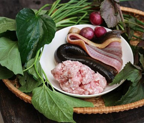 Cuốn thịt vào miếng lươn. Dùng lá lốt cuộn miếng lươn nhồi thịt, dùng hành lá trần qua nước nóng buộc lại cho đẹp. Ảnh: 24h.com.vn.