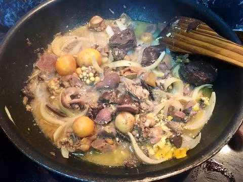 Cho 1 muỗng canh dầu ăn vào chảo, cho đầu hành đập dập vào phi thơm, cho lòng gà trứng non đã ướp vào cùng lúc với hành tây, xào cho vừa chín tới. Thêm chút nước luộc gà vào trong lúc xào để trứng dễ chín hơn. Ảnh: cookpad.com.