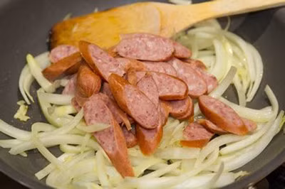 Cho xúc xích vào xào sau khi phi thơm hành. Xúc xích hơi cong thì cho hành tây vào đảo. Nêm dầu hào và chút muối. Cho hành tây vào xào tới khi chín vừa ăn rồi tắt bếp. Ảnh: lamsao.com.