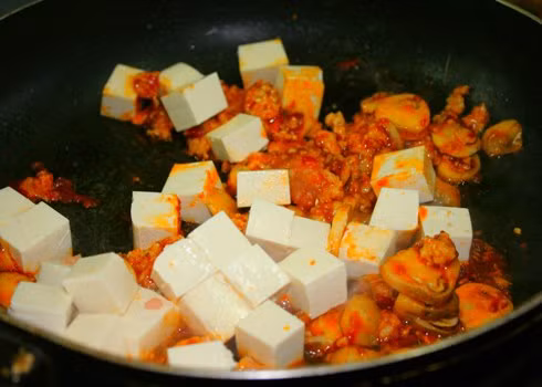 Thịt lợn xay trộn lẫn nửa thìa nhỏ muối, ít hạt tiêu. Cà rốt thái hạt lựu, gừng thái sợi. Ngâm nấm vào thố nước muối pha loãng. Vớt nấm ra để lên rổ cho ráo nước. Đun nóng ba thìa dầu ăn, phi tỏi thơm, đổ thịt lợn vào xào chín, thêm cà rốt, gừng vào đảo cùng. Ảnh: vaobepnauan.vn.