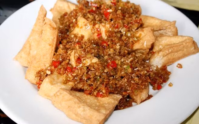 Cuối cùng đổ đậu phụ đã rán vàng vào chảo, dùng đũa đảo đều để sả bám đều bên ngoài bề mặt đậu phụ, sau đó đổ ra đĩa dùng với cơm. Bạn có thể dùng kèm với xì dầu và tỏi. Ảnh: kenhphunu.vn.