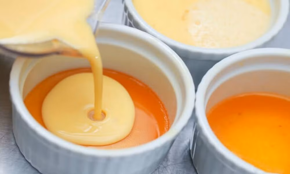 Đổ hỗn hợp vào hũ đựng, cho vào nồi hấp từ 30-40 phút. Sau đó lấy bánh ra, đặt vào thau nước lạnh cho bánh nhanh nguội, tiếp tục ủ trong tủ lạnh trong vòng 15 phút. Làm thạch rau câu: Cho 2 thìa bột rau câu, 400ml nước, đường vào một âu nhỏ, khuấy đều rồi bắc lên bếp đun sôi ở lửa nhỏ. Ảnh: JAMJA.vn.