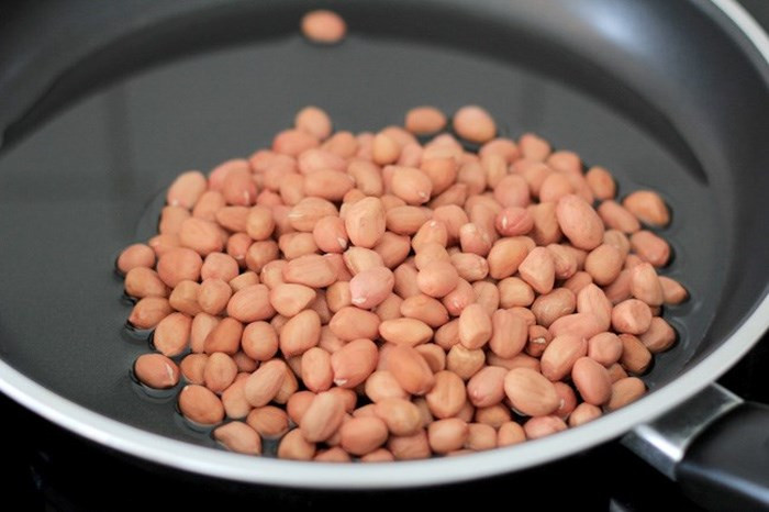 Đồ dầu lạc vào chảo, đun hơi nóng rồi đổ lạc vào rang đến khi có tiếng nổ tí tách, vỏ nứt và chuyển màu vàng nâu thì tắt bếp. Đặt một lớp giấy lót thấm dầu dưới đĩa rồi vớt lạc đổ vào cho thấm hết dầu. Đặt một chảo khác lên bếp, đổ mật ong vào đun, vặn lửa nhỏ.