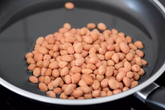 Đồ dầu lạc vào chảo, đun hơi nóng rồi đổ lạc vào rang đến khi có tiếng nổ tí tách, vỏ nứt và chuyển màu vàng nâu thì tắt bếp. Đặt một lớp giấy lót thấm dầu dưới đĩa rồi vớt lạc đổ vào cho thấm hết dầu. Đặt một chảo khác lên bếp, đổ mật ong vào đun, vặn lửa nhỏ.