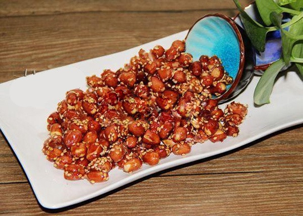 Đổ lạc đã thấm khô dầu vào chảo, đảo đều cho ngấm mật ong rồi tắt bếp. Đổ vừng rang sẵn, đường vào chảo lạc rang và trộn đều. Để cho nguội bớt thì gắp ra đĩa và thưởng thức. Sau khi đậu phộng chiên đường và mật ong đã nguội, có thể cho vào lọ, đậy kín và ăn dần. Ảnh: kenhphunu.com.