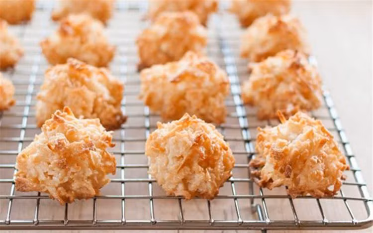Cho 100g dừa sấy, sữa bột và bột mì vào nhào cho thật đều. Nặn bánh: Vo bánh thành nhiều viên tròn nhỏ vừa ăn, sau đó cho lăn qua phần dừa sấy còn lại. Ảnh: Cooky.vn.