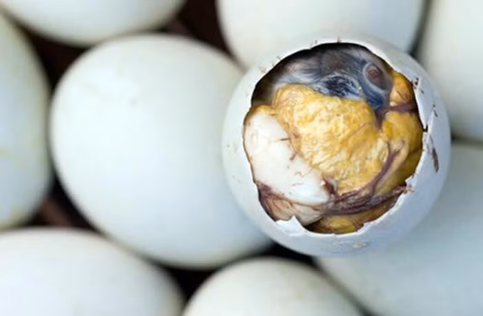 3. Cháo trứng vịt lộn. Nguyên liệu: Gạo, trứng vịt lộn, nấm rơm, rau đắng, hành lá, ngò rí, rau răm, hành tím, muối, hạt nêm, nước mắm, đường. Gạo rang lên cho hơi vàng. Sau đó rửa sạch, bỏ với nồi cùng 1 lít nước, lửa liu riu. Ảnh: Giadungbep.com.