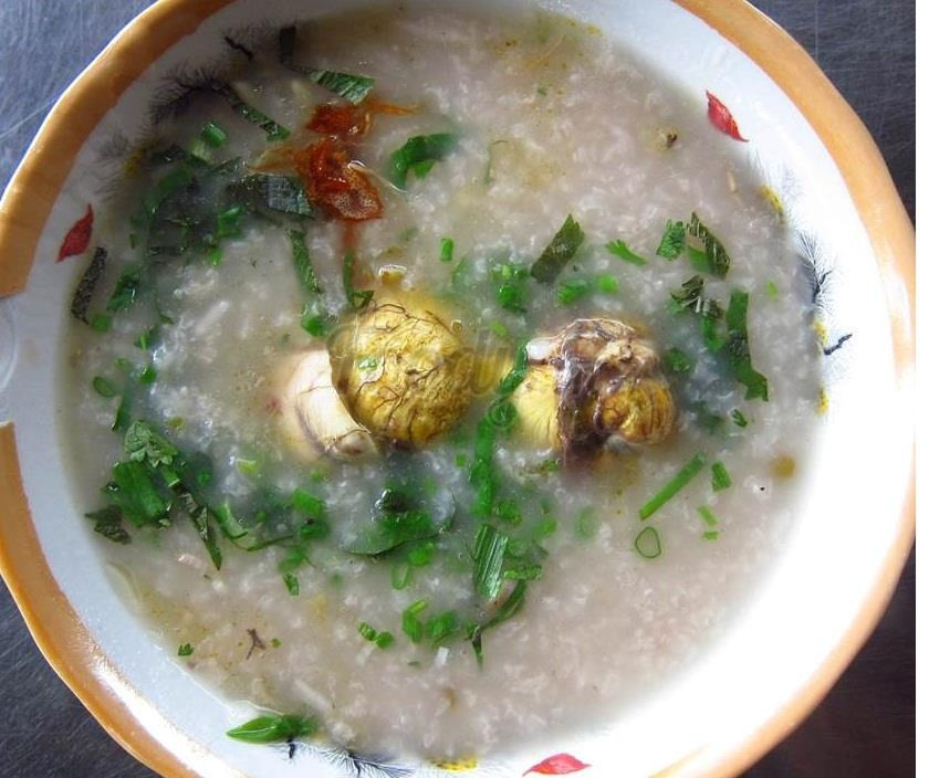 Khi cháo chín, nêm nếm cho vừa ăn, đổ phần nấm rơm vào sau cùng, thêm hành. Tắt bếp. Dùng kèm với rau đắng, thái nhỏ rau răm, rắc thêm chút tiêu. Ảnh: JAMJA.vn.