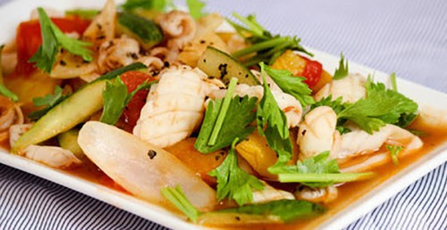 Cho thêm 2 thìa dầu ăn vào, cho dứa, ớt chuông, cà chua, hành tây vào, tiếp tục đảo nhanh tay trong 5 phút, nêm thêm 1 thìa hạt nêm, ½ thìa bột ngọt, ½ thìa đường rồi cho mực vào xào chung, vặn lửa nhỏ vừa, cho hành lá, ngò tây, phần ớt thái lát còn lại vào, đảo nhẹ, nêm nếm lại gia vị cho vừa ăn rồi tắt bếp. Ảnh: GiaDinh.TV.