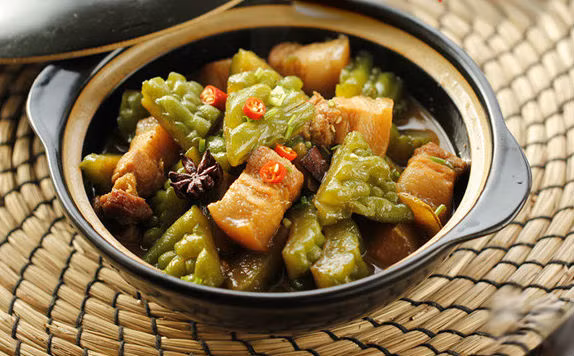 Tiếp đến cho nước dừa tươi cùng các gia vị còn lại vào, rim 10 phút. Cuối cùng cho mướp đắng vào đảo đều, rim cho nước sánh mịn, mướp mềm. Nêm nếm lại cho vừa ăn là tắt bếp. Ảnh: Healthplus.vn.