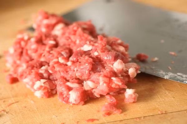 Xay thịt nhuyễn cho vào tủ lạnh 15 phút. Mướp đắng bào mỏng, cho chút muối vào ngâm. Cho 500 ml nước lọc nấu sôi cho 100 g thịt băm vào rồi cho mướp đắng bào vào nấu vừa tới không chín quá, để giữ độ xanh, giòn. Ảnh: monngon.tv.