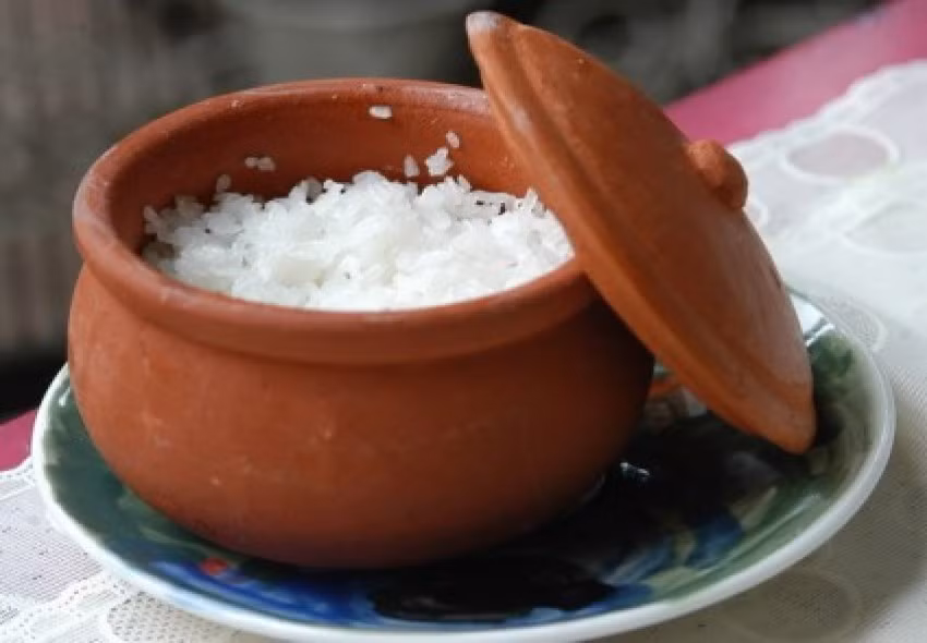 Trong quá trình nấu cần thỉnh thoảng mở nắp niêu và khuấy đều cho cơm tơi. Đến khi cơm bắt đầu chín dẻo và bốc mùi thơm của lá dừa thì hạ lửa nhỏ lại cho cơm chín hoàn toàn. Khi ăn thì dùng đũa cả để xới cơm và bới cơm ra bát để đảm bảo độ xốp cho cơm. Ảnh: AmThuc365.vn.