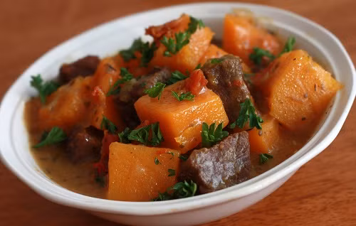 Phi thơm hành, tỏi băm, xào tới khi săn lại, nêm gia vị. Xếp bí đỏ lên trên, đổ chút nước vào kho 15 phút. Dọn ra đĩa, rắc hạt tiêu lên, trang trí với ớt tỉa hoa. Ảnh: 7monngonmoingay.info.