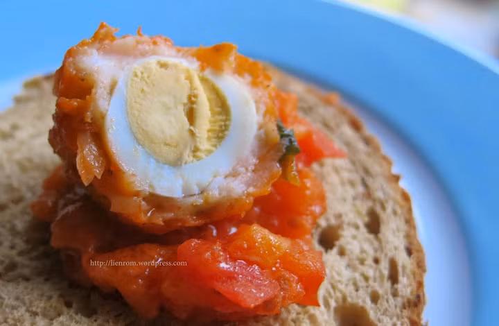 Sau đó, lấy thịt bọc lấy trứng, để hở 1 đầu trứng cho đẹp. Sau đó đem hấp cách thủy khoảng 20 phút. Trong thời gian hấp thịt thì làm nước sauce cà. Cà chua rửa sạch, cắt bỏ hạt, cho vào máy xay sinh tố kèm thêm chút nước. Bắt chảo và làm nóng dầu ăn, cho 1/2 hành tây còn lại vào đảo đều, sau đó cho cà chua đã xay nhuyễn vào. Ảnh: Lienrom.WordPress.com.