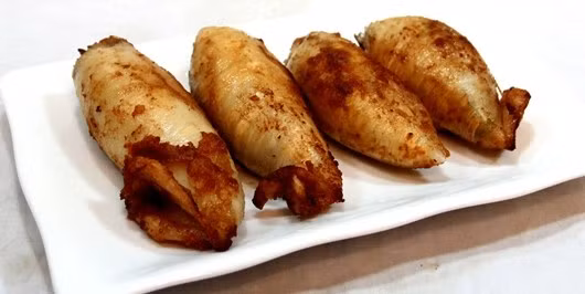 Cho mực vào khay đã bôi mỡ và có tỏi đập dập, tưới mỡ nước lên mực, đưa khay vào lò nướng <200 độ C>. Trước khi lấy mực ra, quết lên mực một lớp mạch nha hòa nước. Mực nướng chín vàng đều là được. Ảnh: kenh14.vn.