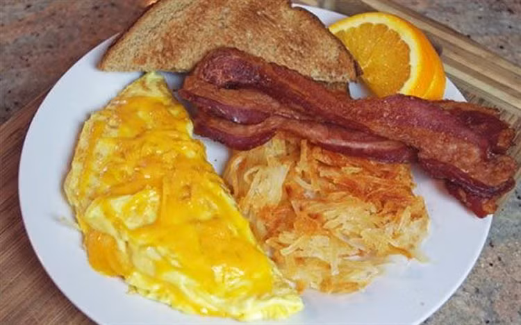 Nghiêng chảo để bơ lan khắc bề mặt. Khi bơ bắt đầu vàng, cho hỗn hợp trứng vào chảo. Dùng đánh trứng đánh nhanh trứng trong chảo 1-2 giây để tạo độ phồng. Khi trứng bắt đầu săn lại, nghiêng chảo để phần trứng ở trên chảy xuống. Rắc bơ lên bề mặt trứng. Cuộn đôi miếng trứng lại. Ảnh: Cooky.vn.