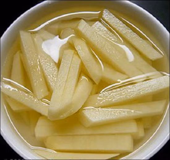 3. Khoai tây chiên bơ. Nguyên liệu: Khoai tây, bơ thực vật, tỏi, muối. Khoai tây mua về rửa sạch, cho vào nồi nước để luộc chín. Sau đó rửa lại bằng nước lạnh, để nguội rồi gọt sạch vỏ khoai. Cắt khoai thành những miếng dài vừa ăn hoặc theo hình thù tùy thích. Ảnh: homnayangi.vn.