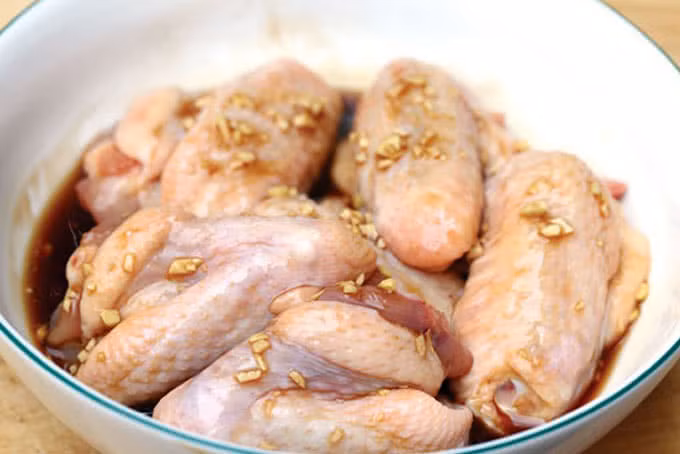 2. Gà chiên bơ. Nguyên liệu: Cánh gà, bơ, rau mùi, cà chua, ớt, tỏi, dầu ăn, xà lách, dưa chua, tiêu, muối, mì chính. Cánh gà làm sạch; để thật ráo, ướp hạt tiêu, muối, tỏi băm, bột ngọt 30 phút cho ngấm. Lăn cánh gà qua bột mì rồi cho vào chảo chiên vàng, vớt ra để ráo. Ảnh: PasGo.vn.