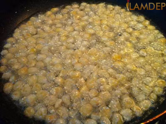 Tiếp tục cho trứng đánh tan vào rổ ngô, dùng tay trộn đều, phần trứng thừa sẽ chảy qua các kẽ rổ. Sau đó, cho ngô đã trộn trứng vào bát đựng bột, trộn đều, khi thấy ngô đã được bao phủ bởi một lớp bột, cho ngô qua rây, lúc này lượng bột dư và mày ngô sẽ rớt ra. Ảnh: iLamDep.vn