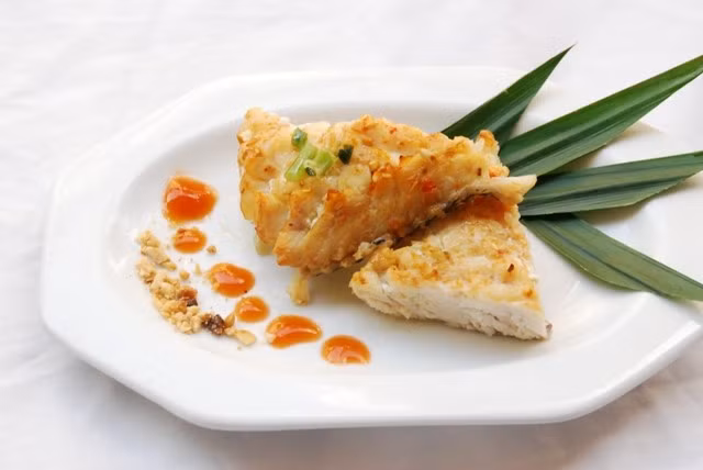 Thỉnh thoảng dùng tay rắc một ít muối lên bề mặt cá trong lúc chiên để muối ngấm vào bột thì khi ăn hương vị sẽ đậm đà hơn. Khi một mặt cá đã chín thì lật miếng cá để chín vàng đều hai bên. Đun lửa nhỏ để miếng cá chiên không bị cháy bên ngoài và thịt cá bên trong chín đều. Ảnh: BepGiaDinh.com.