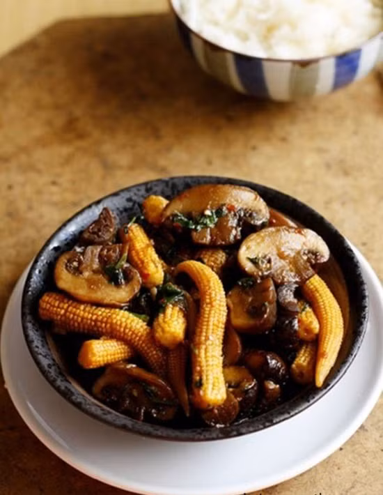 Cho ngô bao tử vào kho cùng, thêm muối, hạt nêm cho vừa miệng, đun tiếp khoảng 10 phút nữa. Tắt bếp, thêm rau mùi, hành lá thái nhỏ vào, múc ra đĩa dùng làm món mặn ăn với cơm. Ảnh: toinayangi.vn.