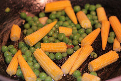 Đậu Hà Lan, ngô bao tử rửa sạch, ngô bao tử cắt làm đôi. Hành tây bóc bỏ vỏ khô, thái lát mỏng. Phi hành thơm, cho cồi sò điệp vào xào khoảng 3 phút, đổ ra bát để riêng. Dùng chảo đó, rưới thêm một ít dầu ăn, cho đậu và ngô vào xào chín. Ảnh: congthucmonngon.com.