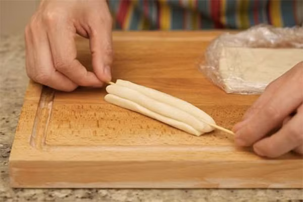 Trộn bột với nước. Nhào kỹ khối bột rồi ủ khối bột khoảng 15 phút . Nhào lại một lần. Lặp lai bước trên 2 lần. Cán khối bột ra thành miếng dày 2 cm rộng 5 cm. Bọc khối bột lại bằng giấy nilon có tráng một ít dầu ăn cho khỏi dính. Ủ khoảng 3 đến 5 giờ. Ảnh: momkitty.com.