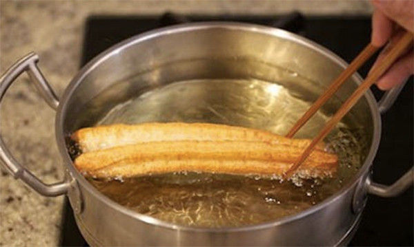 Phủ bột khô lên mặt bàn trước khi kéo khối bột dài ra để chuẩn bị rán. Kéo khối bột ra chiều rộng khoảng 3-4cm. Cắt từng miếng 2 x 4 cm hoặc 1.5 x 3 cm. Đặt miếng nọ lên miếng kia. Dùng que nhỏ ấn dọc ở giữa miếng bột để dính hai miếng với nhau. Ảnh: Ameovat.com.