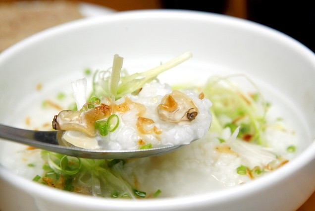 Sau đó, đun nóng dầu ăn phi thơm hành khô xắt lát nhỏ. Khi hành chín, trút hành ra đĩa để nguội rồi cho phần thịt ngao vào xào săn, thịt ngao để ăn với cháo nên xào hơi mặn một chút. Hành lá, rau răm rửa sạch thái nhỏ. Múc cháo chín ra bát, rắc hành lá, rau răm, hành phi, thêm thịt ngao xào săn, rắc tiêu, ớt bột và thưởng thức. Ảnh: homnayangi.vn.