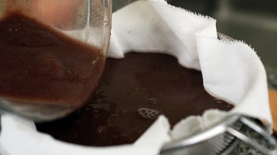 Thêm 2 – 3 cup nước vào, lọc đậu đỏ qua rây, dùng thìa ấn xuống để chiết lấy nước. Đặt 1 miếng vải xô vào lòng rây, đổ nước đậu đỏ vào, đợi vài phút cho nước chảy xuống bát. Túm chặt miếng vải lại và bóp lấy phần nước đậu còn sót lại. Cho bã đậu vào nồi, thêm đường, muối, vani vào, khuấy đều khoảng 3 – 5 phút. Ảnh: kenh14.vn.