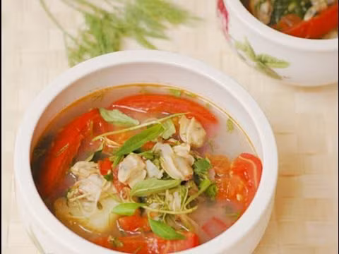 Cho dầu ăn vào nồi, phi thơm hành, cho cà chua cùng dứa vào đảo đều trong 2 phút. Cho nước luộc ngao vào đun sôi trong 5 phút. Thêm hạt nêm. Cho thịt ngao vào đun cùng. Nước sôi lại 2 phút là tắt bếp, thả rau răm cùng hành tươi vào. Ảnh: youtube.com.