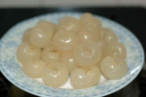 Cho nước dừa tươi vào nồi nấu sôi, nước sôi cho từ từ bột rau câu, đường vào khuấy đều. Khi rau câu tan thì nấu thêm ít phút nữa với lửa nhỏ cho rau câu được nở và trong. Tiếp đến cho nhãn vào quấy đều, tắt bếp. Ảnh: Blog.Beemart.vn.