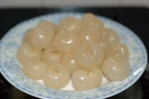 Cho nước dừa tươi vào nồi nấu sôi, nước sôi cho từ từ bột rau câu, đường vào khuấy đều. Khi rau câu tan thì nấu thêm ít phút nữa với lửa nhỏ cho rau câu được nở và trong. Tiếp đến cho nhãn vào quấy đều, tắt bếp. Ảnh: Blog.Beemart.vn.