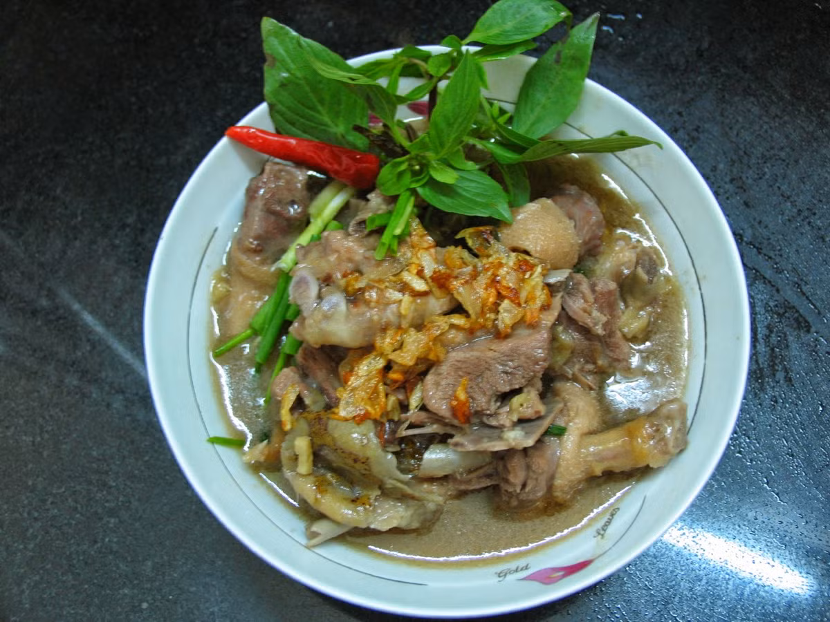 Khi nồi vịt om sấu sôi lại, thì thả phần sả còn lại cắt khúc dài chừng 4cm vào cho thơm. Ninh nhỏ lửa chừng 20 phút. Khi thấy sấu nhừ thì dầm nhuyễn sấu để phần thịt ngấm đủ vị của nước dùng. Ảnh: homnayangi.vn.